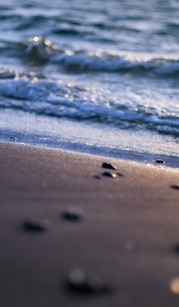 Мокрый морской песок омывает вода