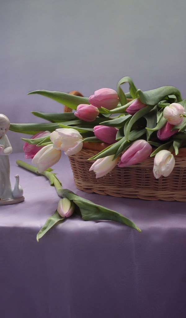 Корзина тюльпанов на столе со статуэткой