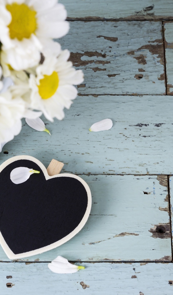 Черное сердце с букетом ромашек на сером столе