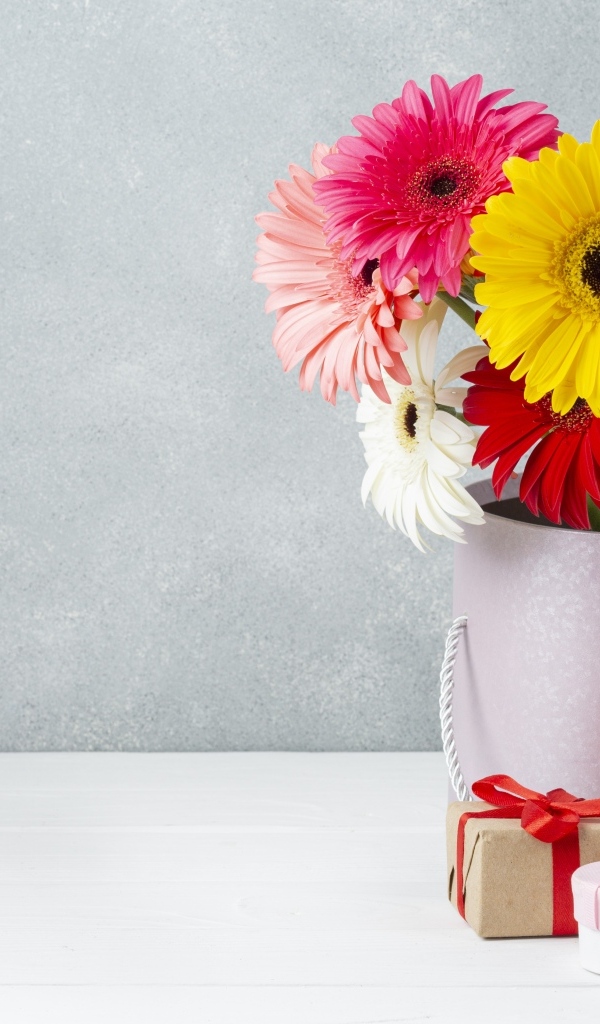 Букет разноцветных цветов герберы на столе с подарками