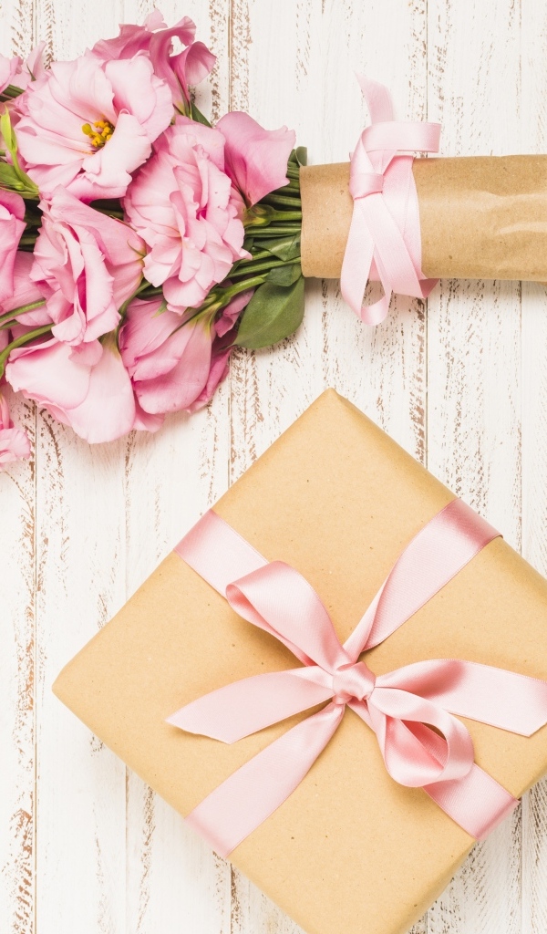 Букет розовых цветов эустомы с подарком на деревянном фоне