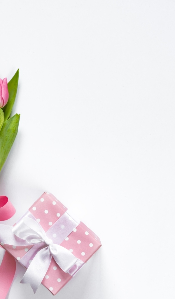 Букет розовых тюльпанов с лентой на столе с подарком