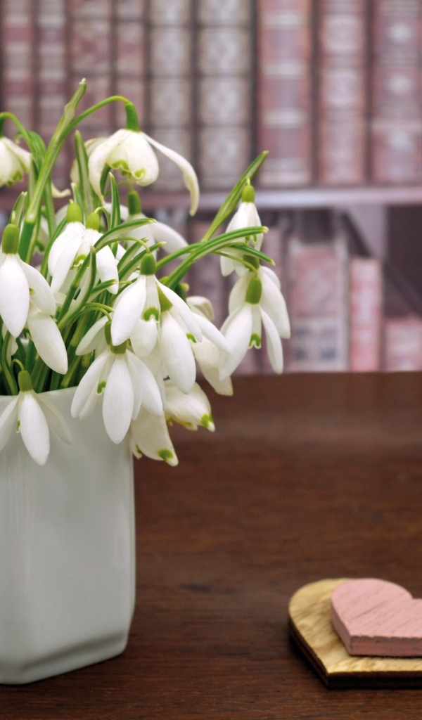 Букет белых подснежников в вазе на столе с сердечками