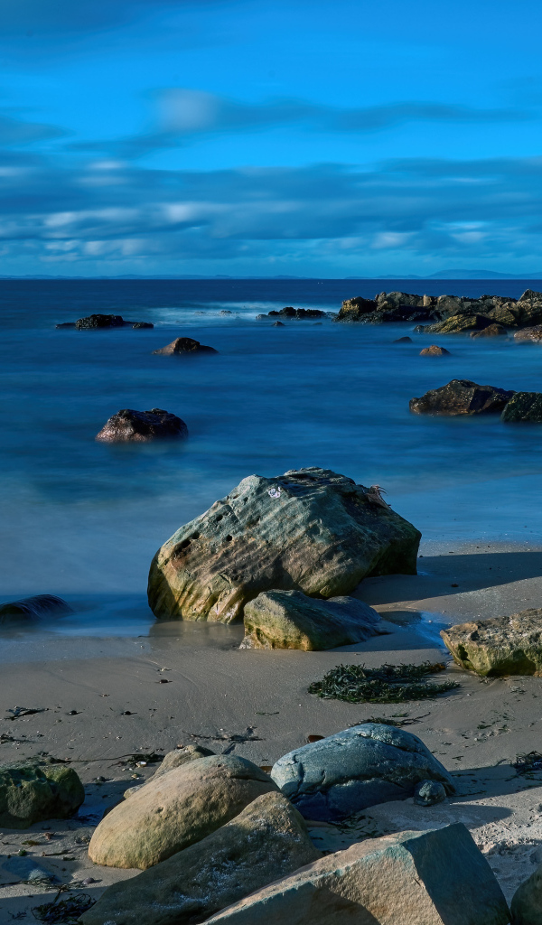 Большие камни на мокром песке у спокойного моря