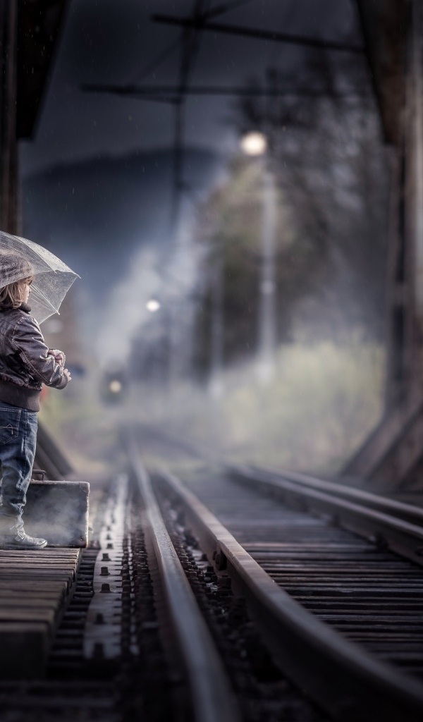 Ребенок под зонтом у железной дороги