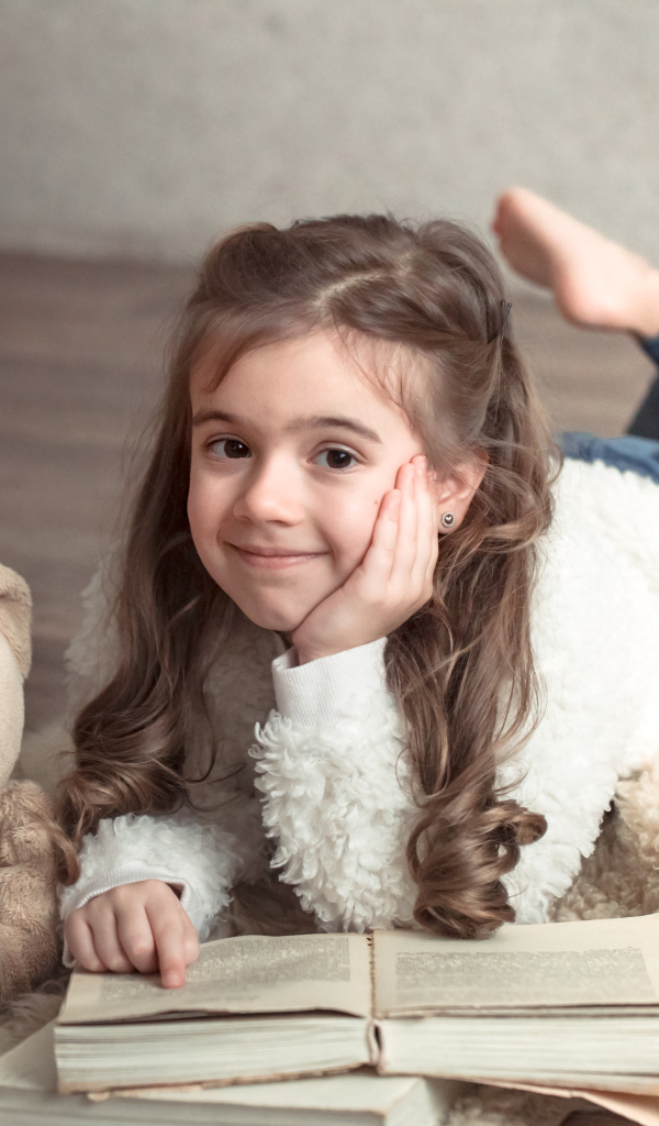 Девочка с медведем и книгой лежит на полу