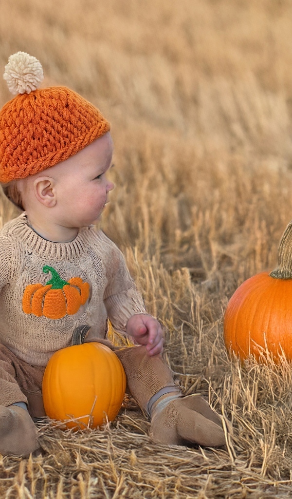 Маленький ребенок сидит на поле с тыквами