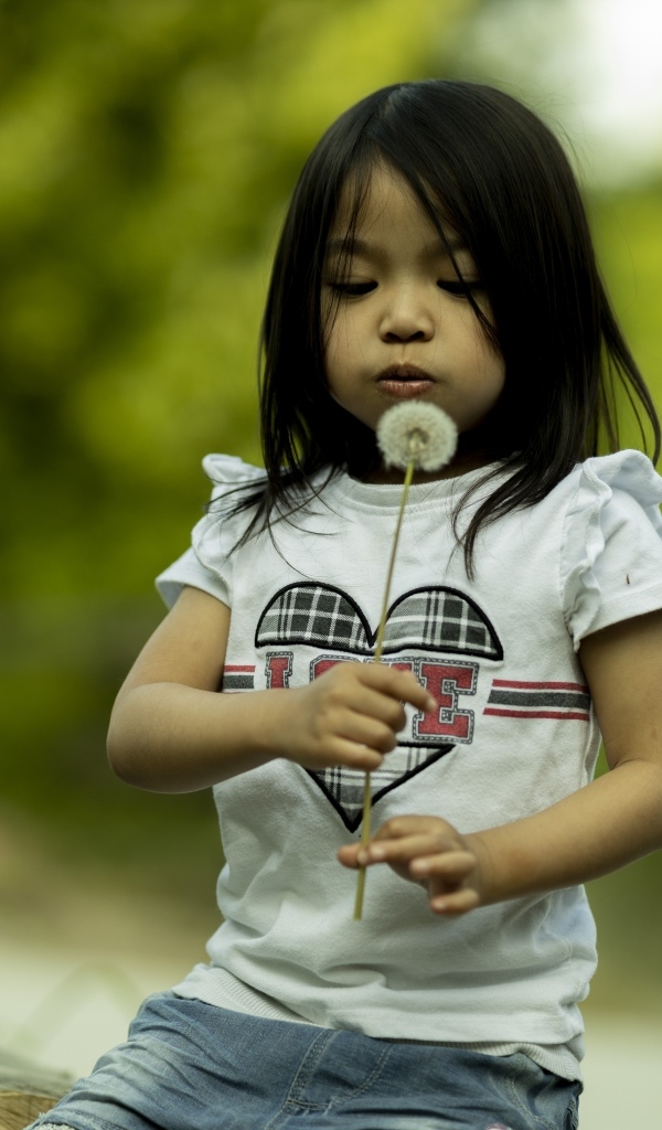 Маленькая девочка азиатка с одуванчиком в руках