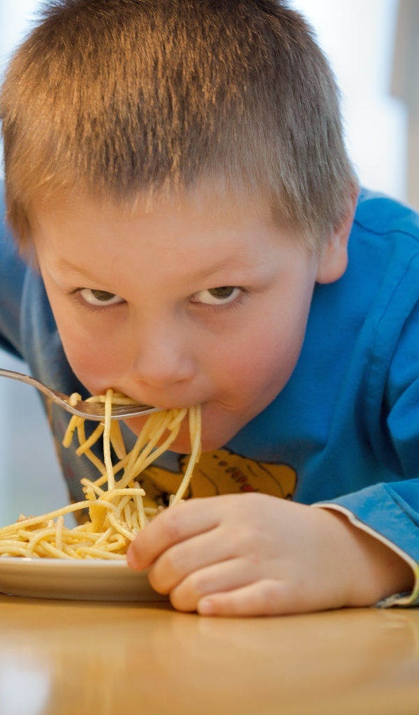 Маленький мальчик ест макароны