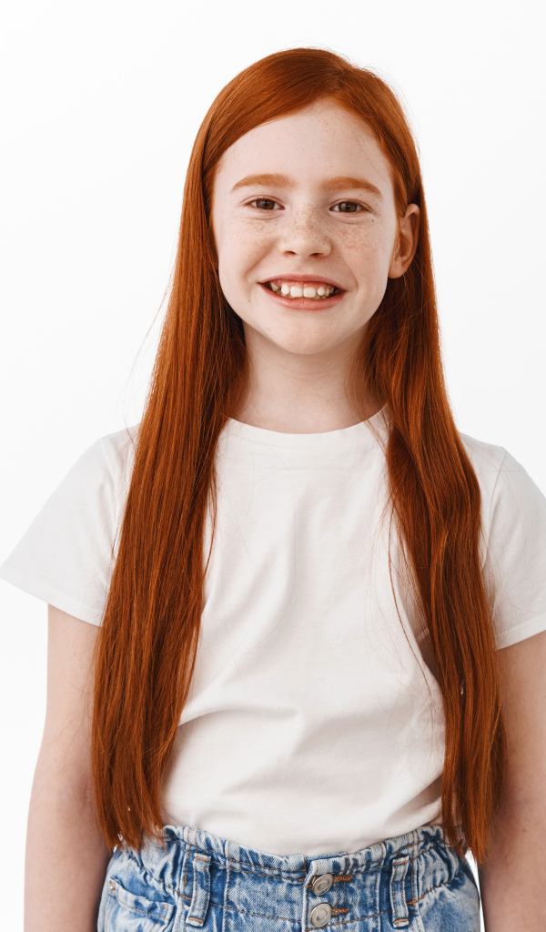 Улыбающаяся рыжеволосая девочка на белом фоне