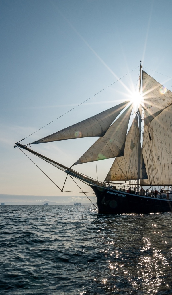 Корабль с белыми парусами в лучах солнца