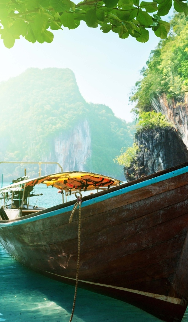 Деревянная рыбацкая лодка в воде на тропическом пляже