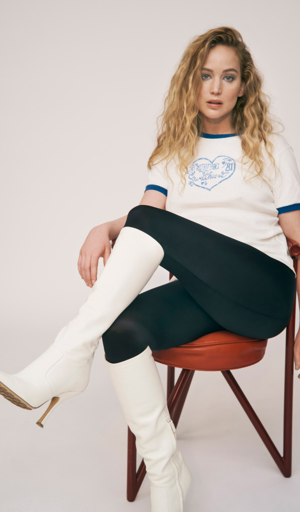 Актриса Дженнифер Лоуренс сидит на стуле на сером фоне