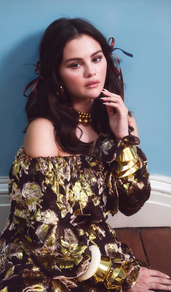 Актриса Селена Гомес на диване на фоне серой стены