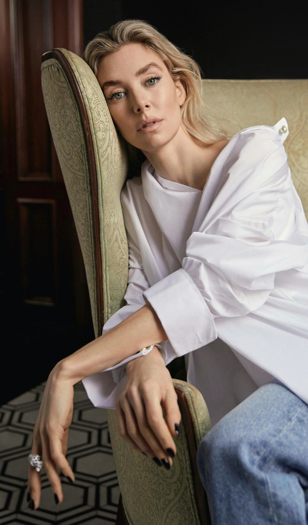 Актриса Ванесса Кирби в белой рубашке сидит на кресле
