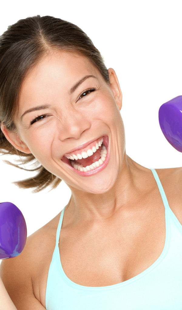 Веселая спортивная девушка с гантелями в руках