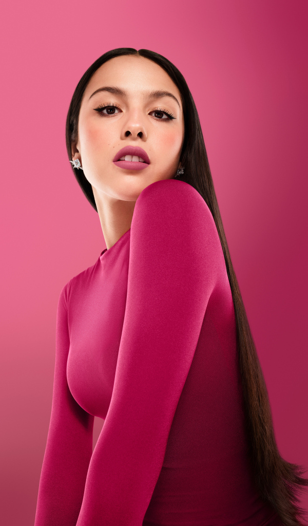 Длинноволосая актриса Оливия Родриго на розовом фоне