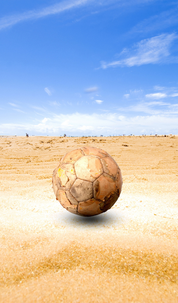 Старый футбольный мяч на песке