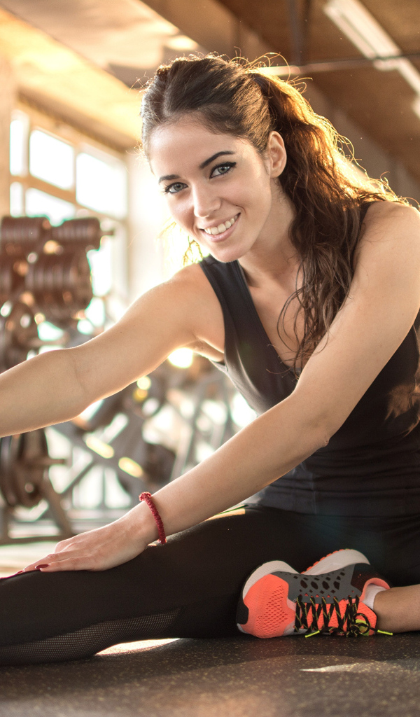 Спортивная улыбающаяся девушка делает растяжку