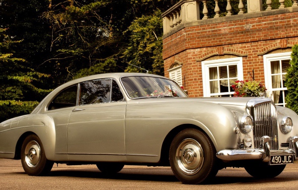 Белый автомобиль у кирпичного дома