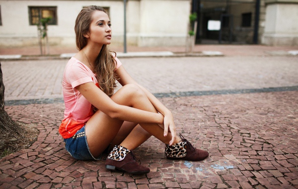 Брюнетка в шортах сидит на дороге