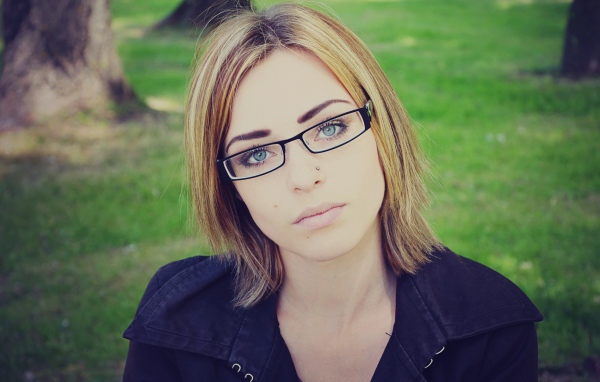 Девушка блондинка с пирсингом в носу в очках