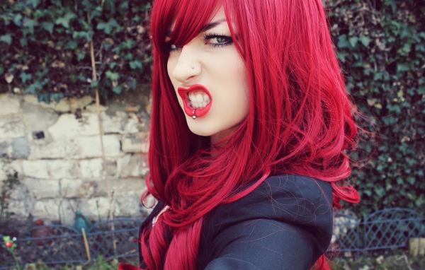 Девушка с красными волосам и пирсингом в носу и губе