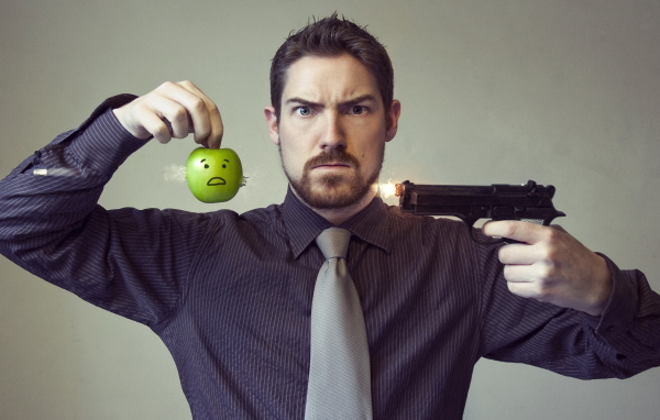 Мужчина стреляет в яблоко