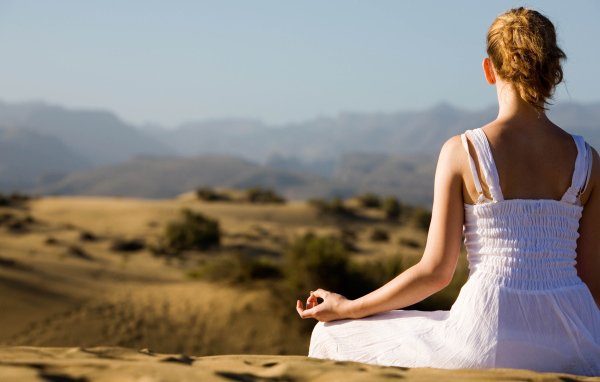 Девушка медитирует на холме