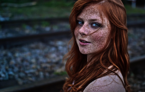 Девушка с веснушками на фоне рельс