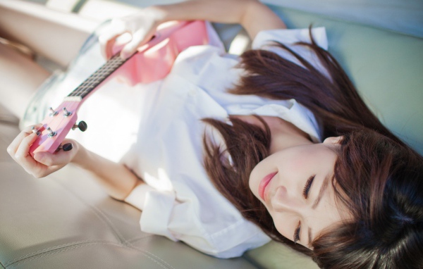 Брюнетка и розовая гитара на диване