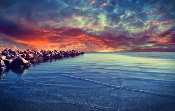 Красный закат над каменистым берегом