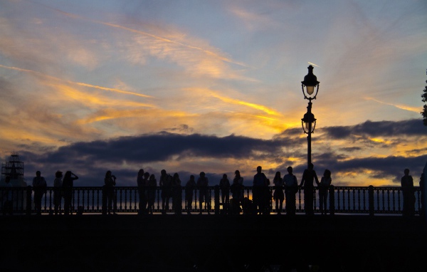 Люди провожают солнце на мосту