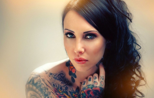 Голубоглазая девушка с татуировкой на руке и плече