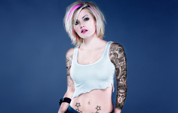 Девушка бунтарка с татуировками на руке и животе