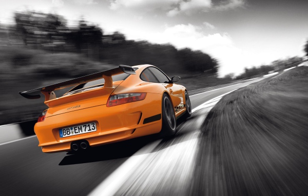 Оранжевый Porsche GT3RS на сером шоссе