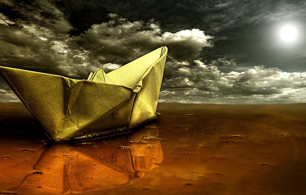 Бумажный кораблик на песке пляжа