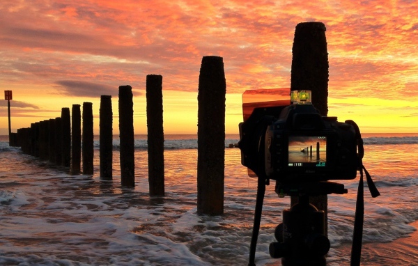 Фотограф снимает закат на берегу моря