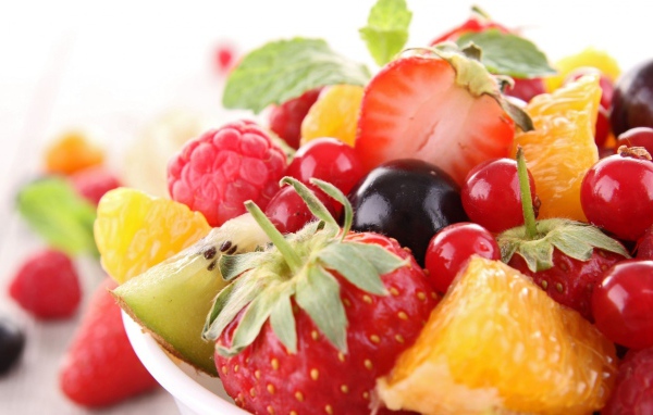 Кусочки спелых фруктов и ягоды на тарелке