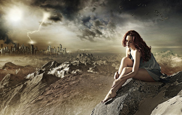 Девушка сидит на камне за городом