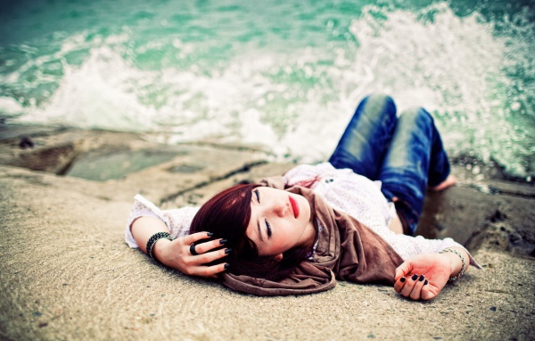 Босая девушка в джинсах лежит на набережной