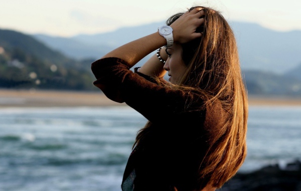 Шатенка с длинными волосами поправляет прическу