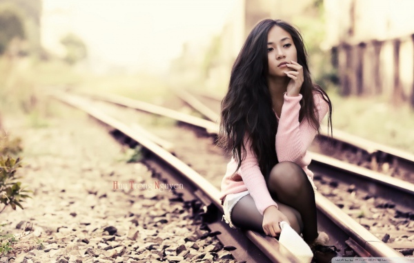 Брюнетка сидит на холодных рельсах