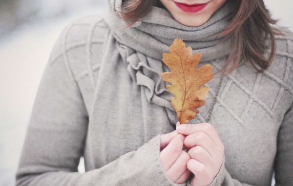 Девушка держит в руках желтый лист