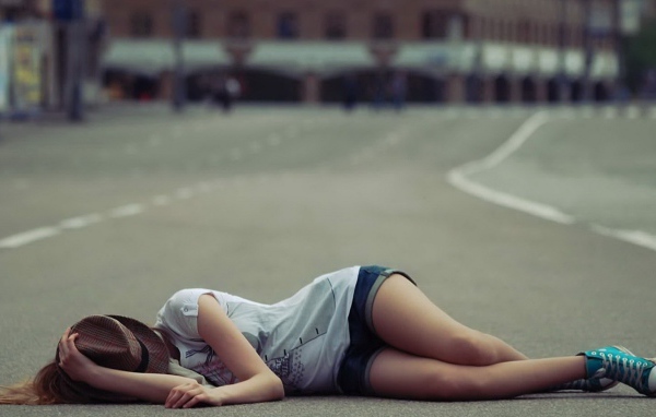 Девушка в шляпе лежит на дороге