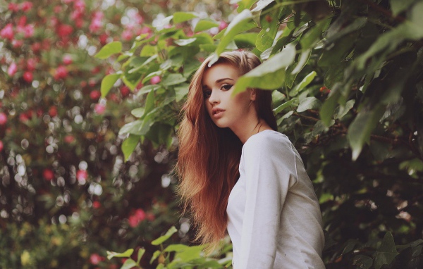 Девушка в белом платье гуляет в саду