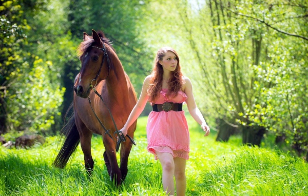 Девушка ведет лошадь под уздцы