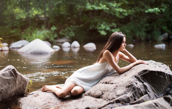 Девушка лежит на камне у реки