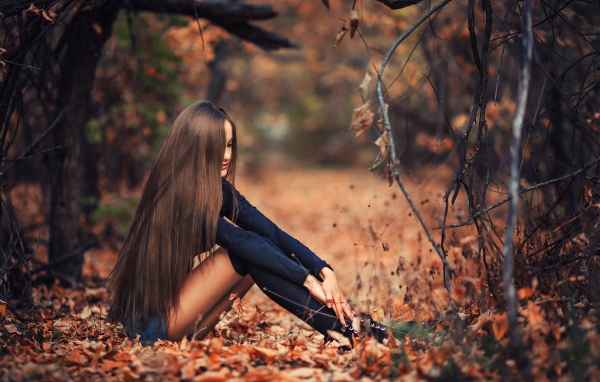 Девушка сидит на осенней листве