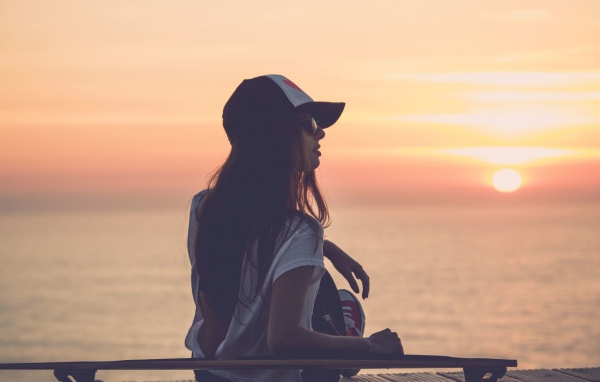 Девушка смотрит на закат на пляже
